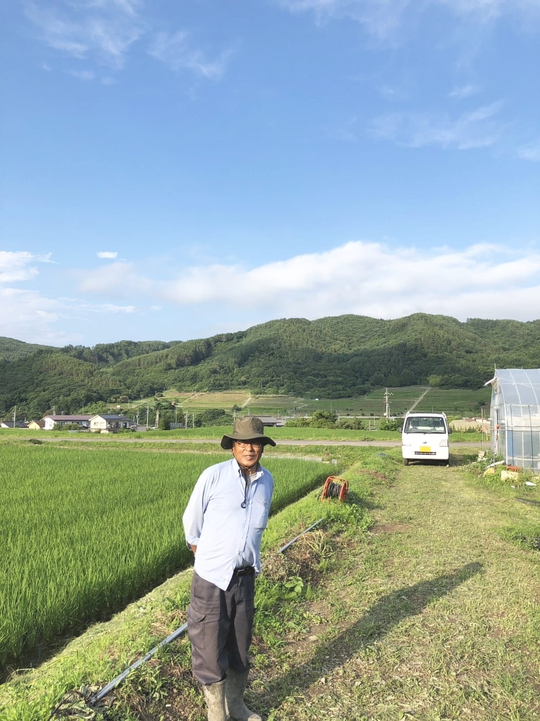 両角農園：水田のそばに立つ両角農園の生産者